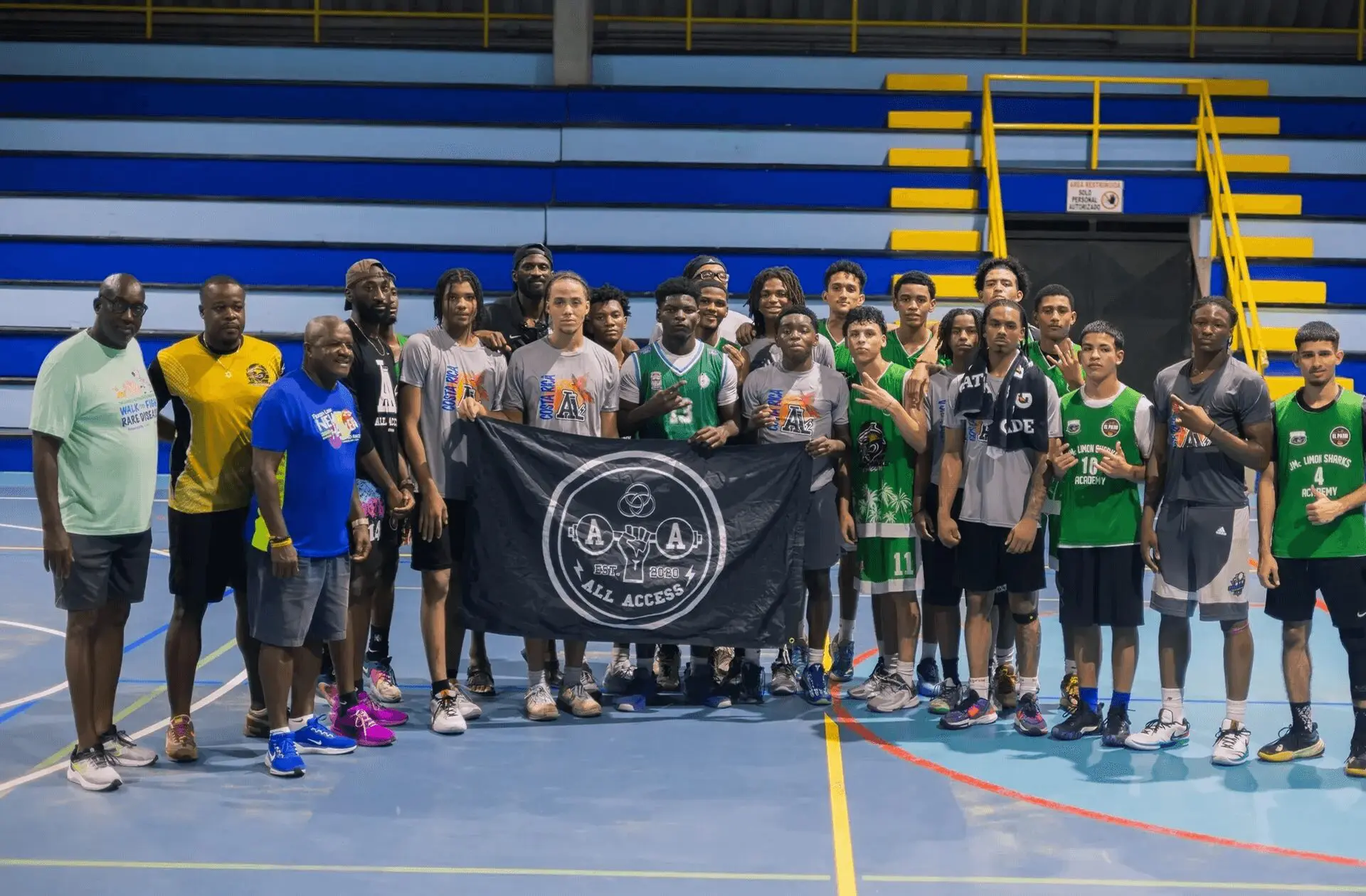 A basketball team posing with a banner on a gym court.