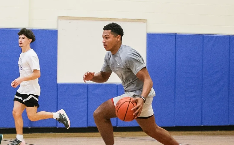 Young man dribbling a basketball indoors.