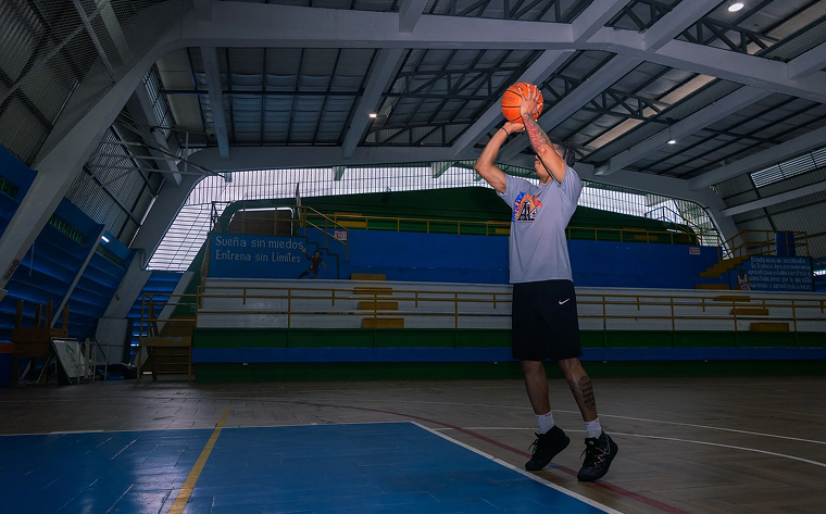 Man preparing to shoot a basketball in an indoor court.