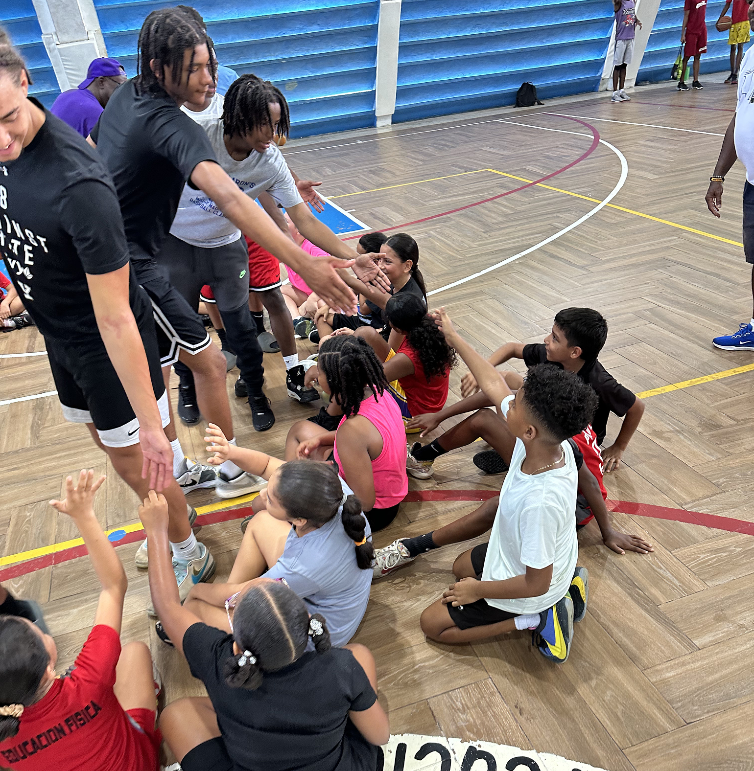 Children and adults engage in a group activity in a gymnasium.