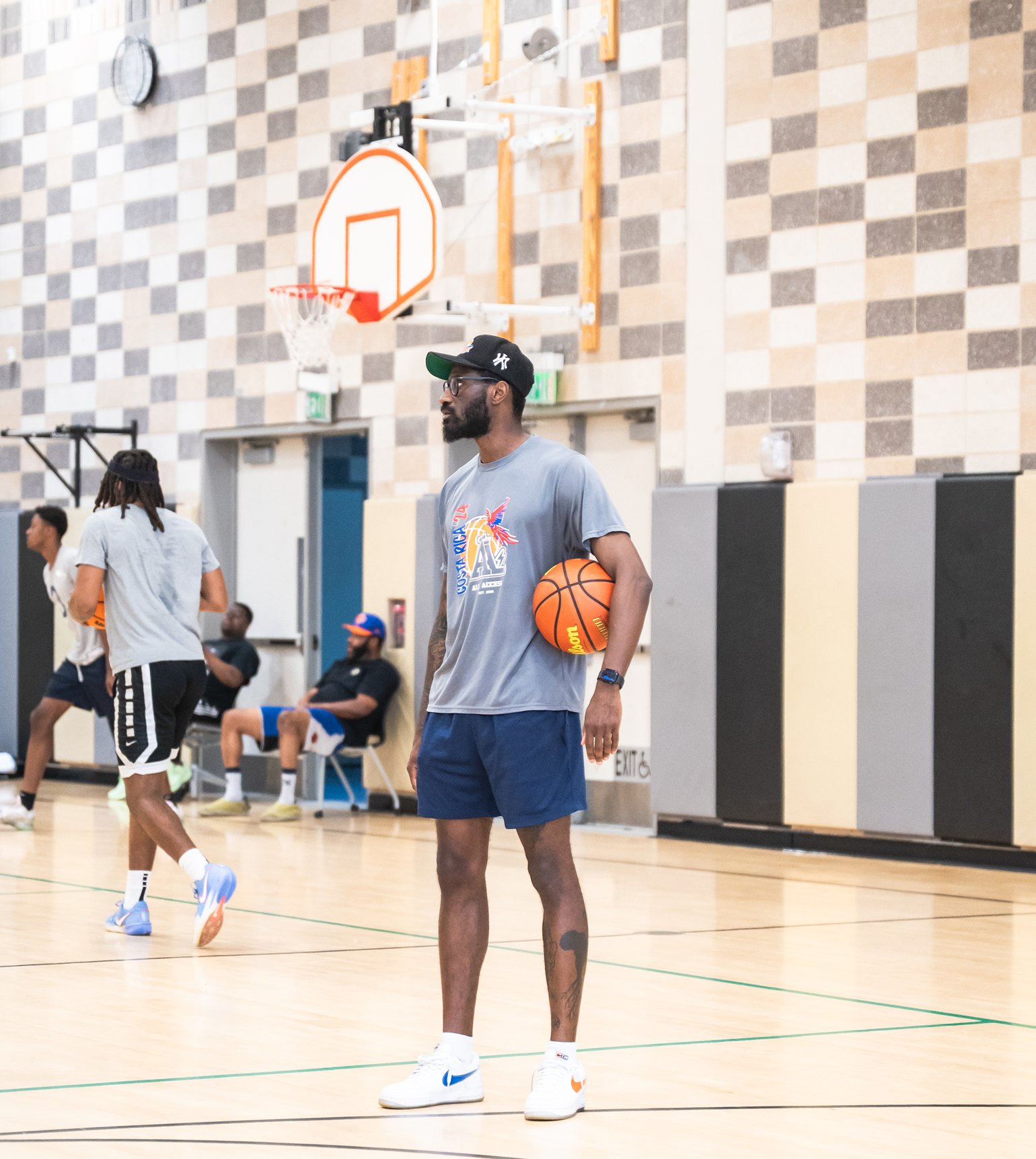 Man in VR headset holding a basketball on an indoor court.