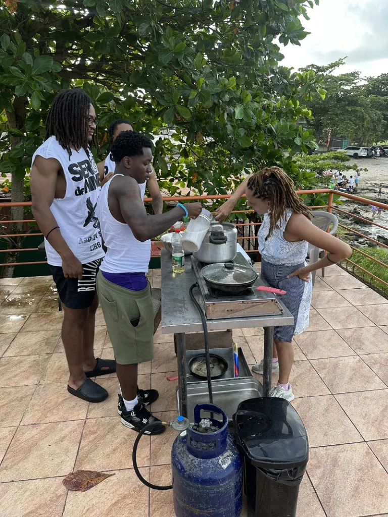 Three people enjoying a cooking activity outdoors on a sunny day.